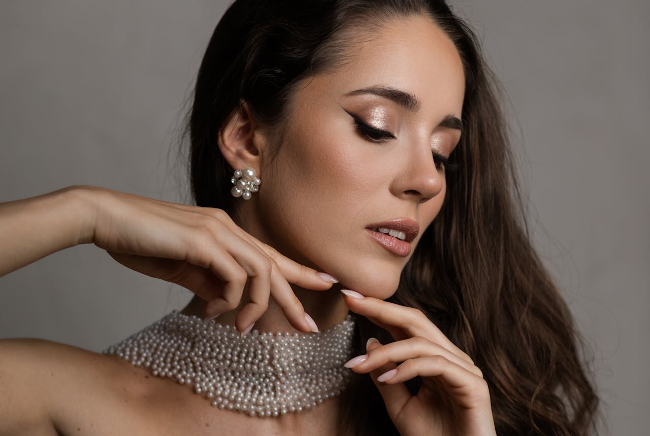 Close-up portrait of a stylish woman wearing pearl jewelry and makeup.